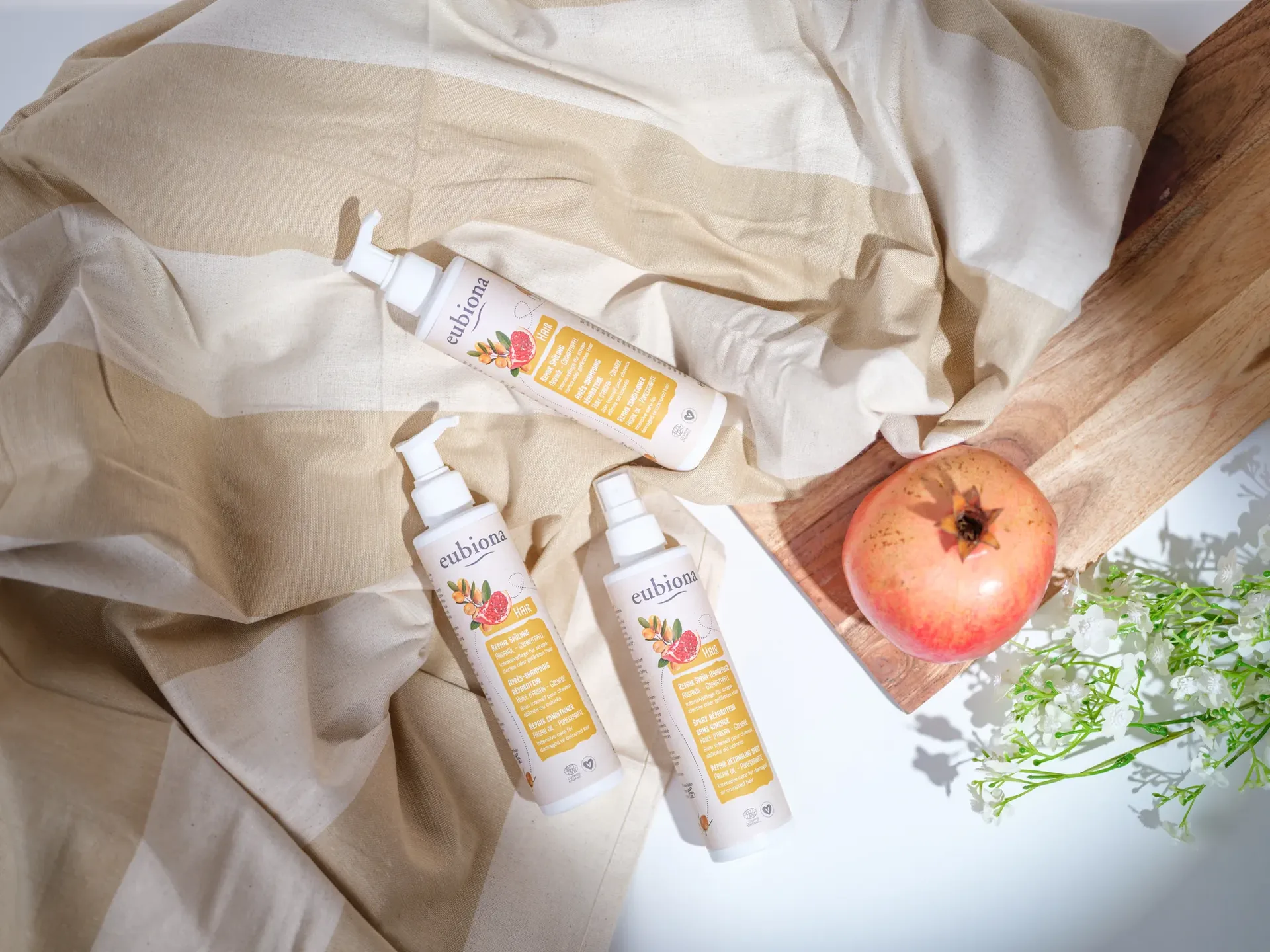 Produkt-Flatlay für Eubiona Naturkosmetik mit Granatapfel auf Holz
