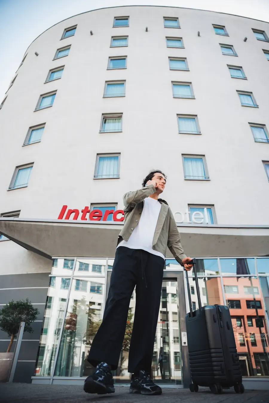 Gast mit Koffer vor der Fassade des IntercityHotel Mainz, von unten fotografiert