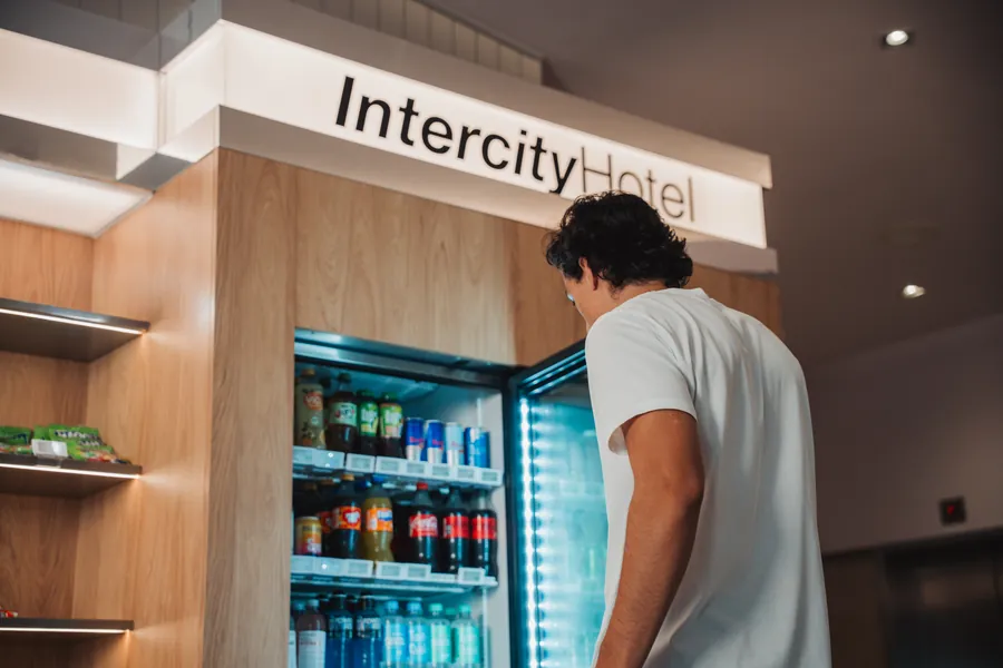 Gast vor dem Kühlschrank der Snackbar unter dem IntercityHotel-Schriftzug