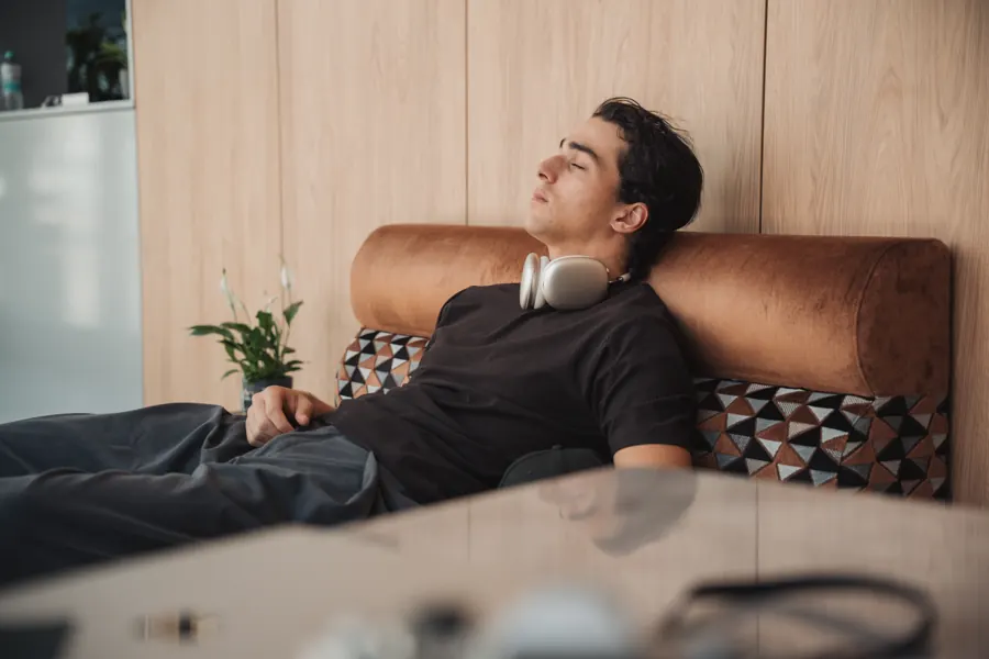 Gast macht auf dem Lobbysofa eine Pause, Kopfhörer um den Hals