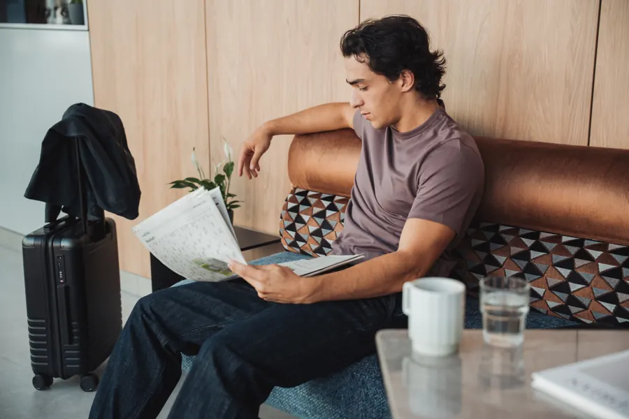 Gast liest Zeitung in der Lobby, Kaffee auf dem Tisch