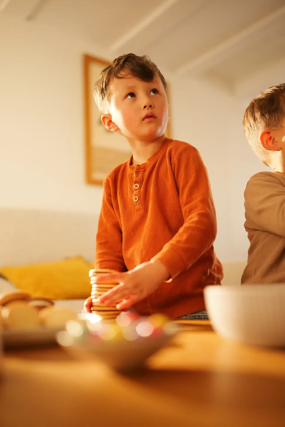 Kind mit Keksen im orangen Shirt, Familien-Content Pural