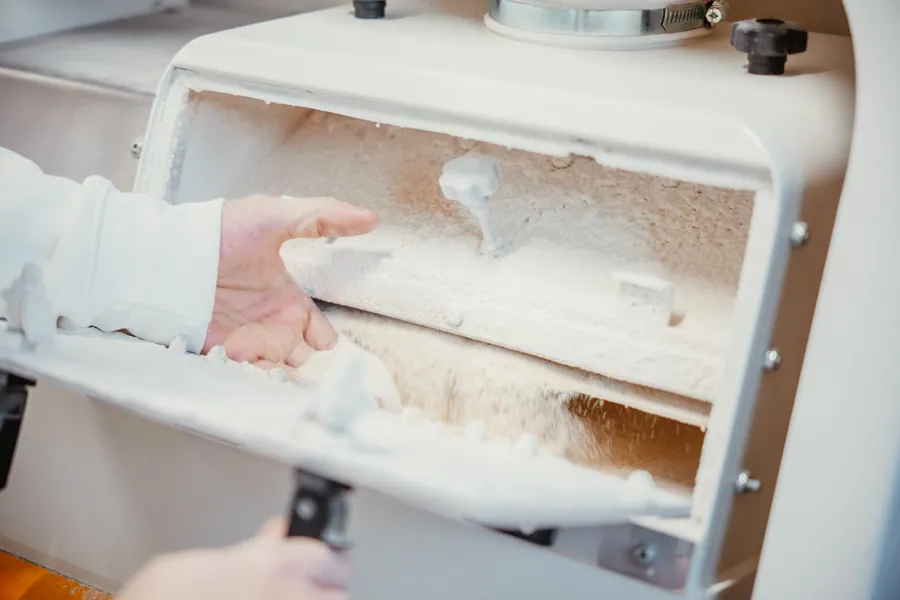 Hände prüfen Mehl an der Maschine