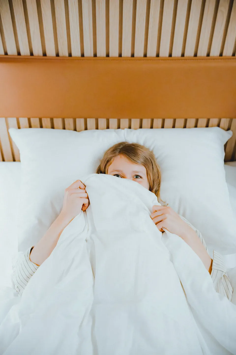 Kind versteckt sich unter der Bettdecke, Familien-Content Zleep